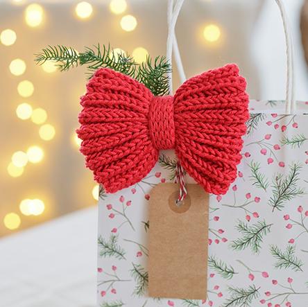 Holly Red Bow / DROPS Extra 0-1628 - Knitted bow/Christmas decoration in DROPS Cotton Merino. Piece is worked from side to side in English rib with I-cord and double knit. Theme: Christmas.