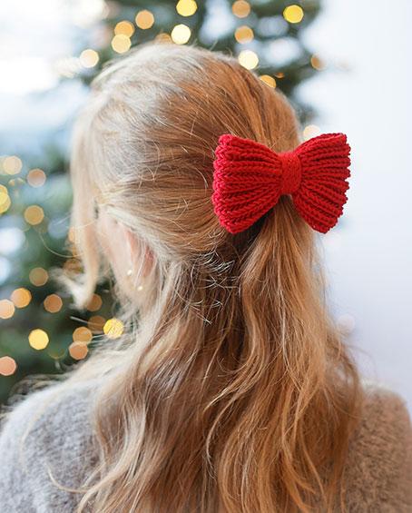 Holly Red Bow / DROPS Extra 0-1628 - Knitted bow/Christmas decoration in DROPS Cotton Merino. Piece is worked from side to side in English rib with I-cord and double knit. Theme: Christmas.